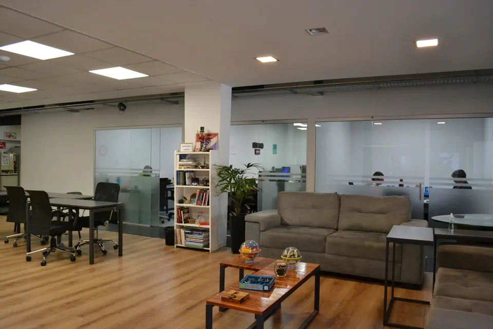 Área de estar con sillones, mesa ratona y biblioteca, junto a las mesas de trabajo