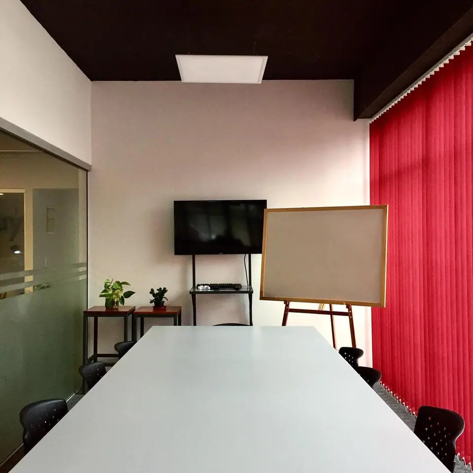 Sala de reuniones con mesa larga, televisor y pizarra